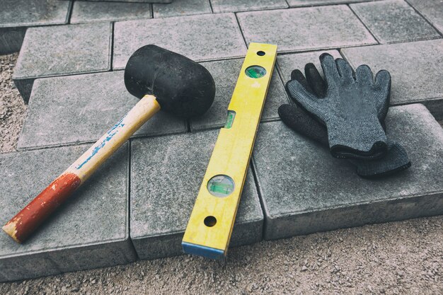 Handschoenen, hamer en bouwniveau op straatsteen