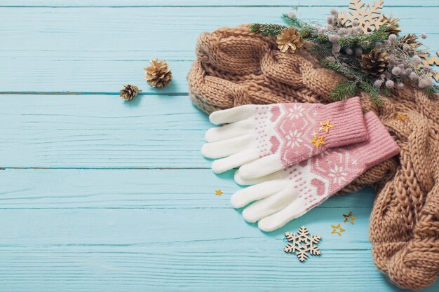 Handschoenen, sjaal en kerstversiering op blauwe houten tafel