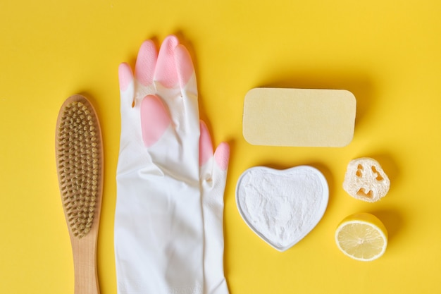 handschoenen sponzen frisdrank en penseel op gele achtergrond eco reinigingsconcept