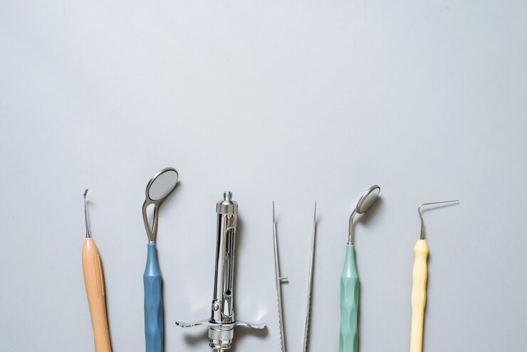 Foto handschoenen, tandspiegel, anesthesiespuit, sondes, pincet op een blauw