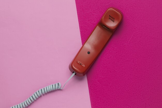 Handset op roze papieren achtergrond. Minimalistisch kantoorconcept. Bovenaanzicht