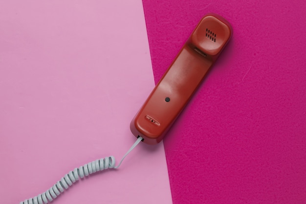 Handset on pink paper background. Minimalistic office concept. Top view