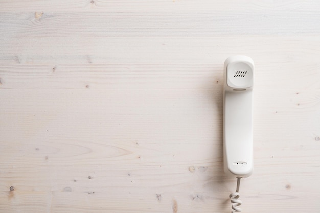 Microtelefono di un telefono fisso bianco posizionato su una tavola di legno normale