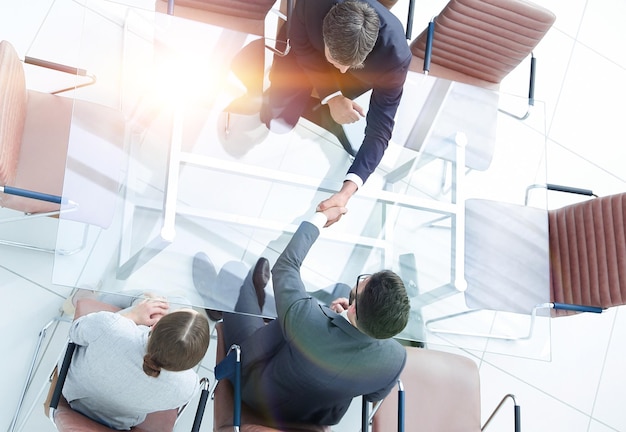 Handshake across the table meeting around a boardroom table