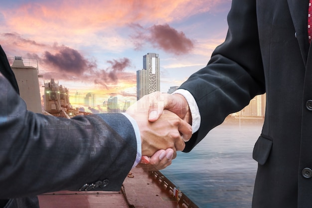 Handshake agreement of businessman with partnership on cargo ship import to city background