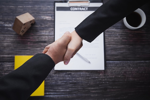 Foto stretta di mano dell'ufficio dell'agente bancario con il cliente o il cliente, vendita casa, affitto residente e acquisto appartamento o concetto immobiliare, vista dall'alto di uomo d'affari stringere la mano con il banchiere dopo aver negoziato con successo