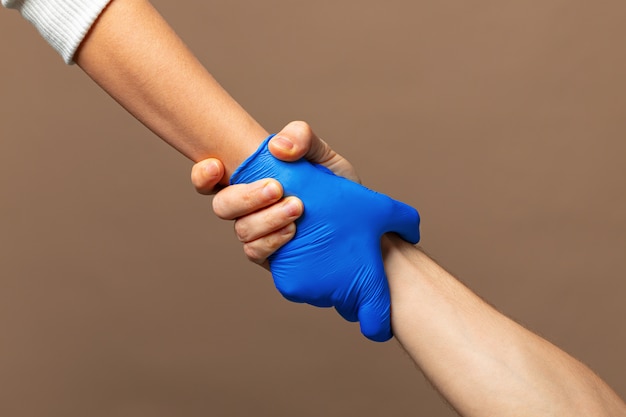 Stretta di mano in guanti blu, concetto di aiuto. igiene personale durante una pandemia