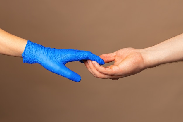 青い手袋で握手、コンセプトを助けます。パンデミック時の個人衛生