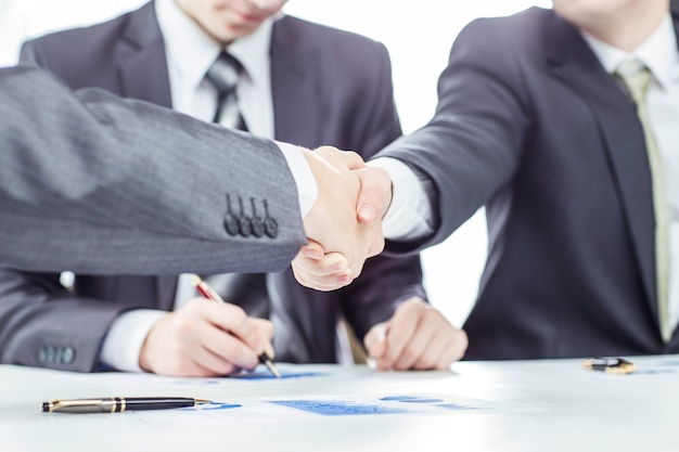 handshake of business partners on the background of a lawyer and financial documents