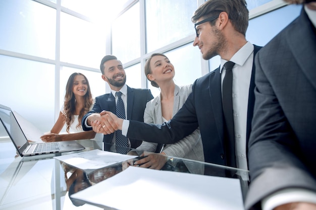 Handshake business partners sitting at the negotiating tablethe concept of cooperation