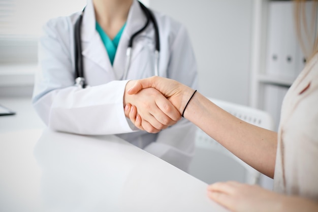 Handshake doctor and patient sitting at the table, closeup.