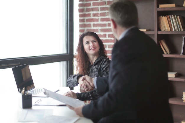 Handshake Manager and client sitting at your Desk in the office.