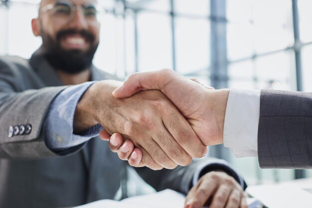 handshake in the office of two businessmen at the desk