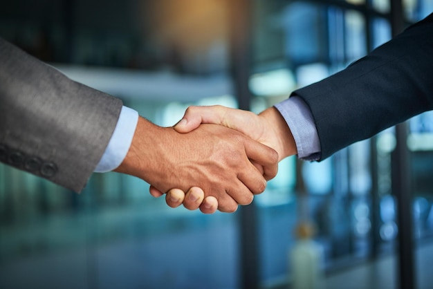 A handshake showing teamwork collaboration and togetherness by business colleagues after a meeting in the office A successful agreement has been reached by male coworkers in a business deal