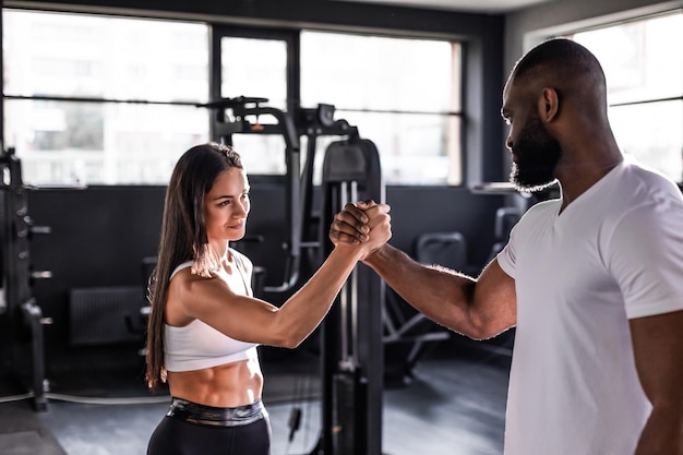 Photo handshake of sporty african man with woman greeting partner exercise workout at fitness gym