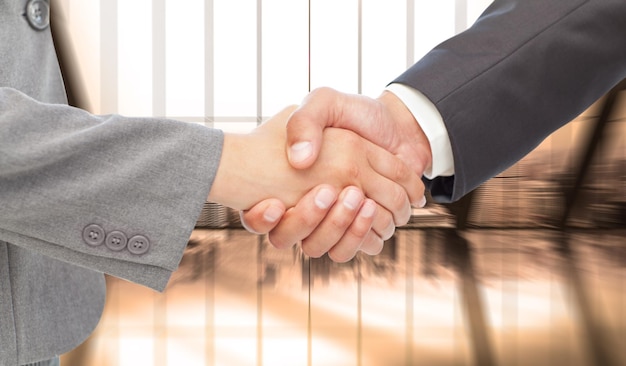 Handshake between two business people against room with large window looking on city