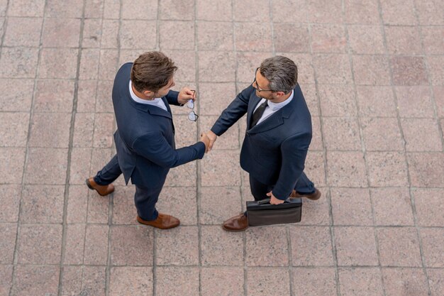 Photo handshake with partner in the city for greeting business men in suit shaking hands outdoors business