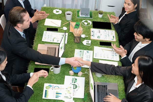 Foto stretta di mano tra green business partnership sul tavolo di riunione dopo aver realizzato una soluzione aziendale di successo per risolvere il riscaldamento globale con l'implementazione di una regolamentazione eco-compatibile