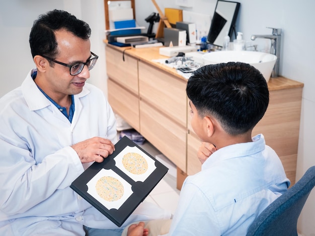 Foto l'optometrista indiano handsom ottiene il daltonismo testato un bambino ragazzo paziente presso la moderna clinica optometry concept