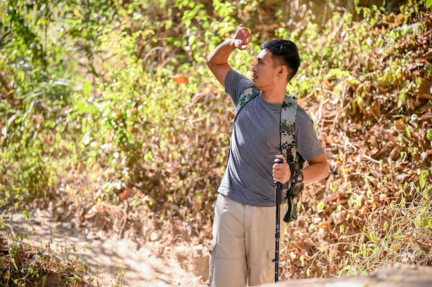 Handsome and active Asian man with trekking gear walking through the Rocky Mountain trail