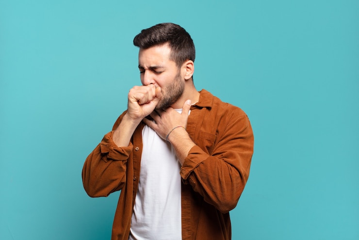Photo handsome adult blond man feeling ill with a sore throat and flu symptoms, coughing with mouth covered