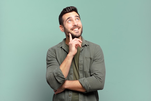 Handsome adult blond man smiling happily and daydreaming or doubting, looking to the side