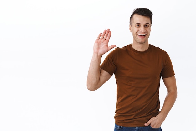 Handsome adult caucasian man saying hi friendly man greet neihbour while standing on balcony selfdistancing during quarantine waving hand in hello greeting gesture smile happy