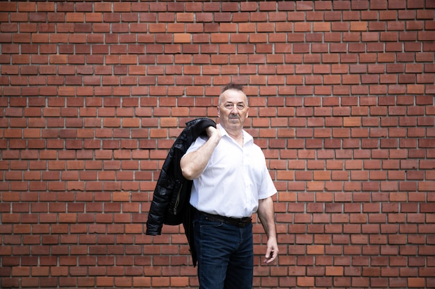 Photo handsome adult man against a brick wall