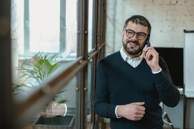 Handsome adult man talking on smartphone and looking away