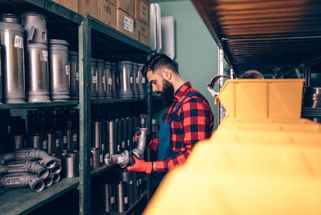 Handsome adult man working in car and truck spare parts warehouse.