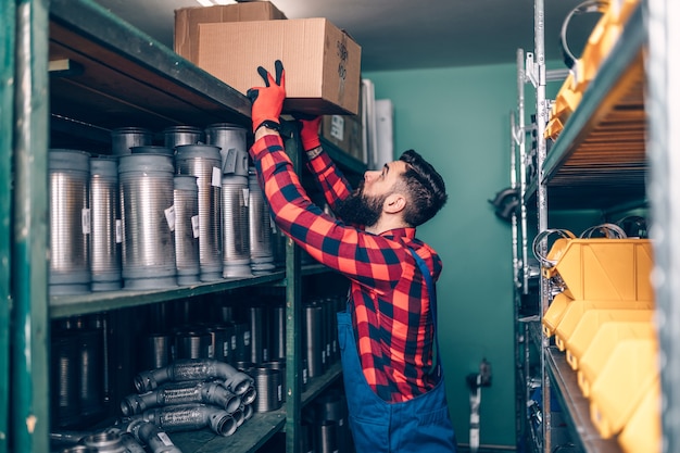 Handsome adult man working in car and truck spare parts warehouse.