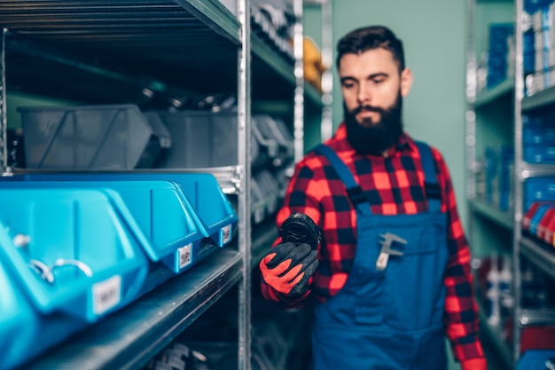 Handsome adult man working in car and truck spare parts warehouse.