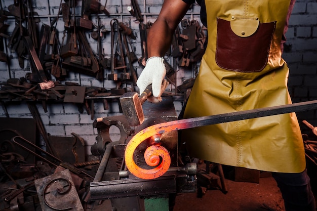 Handsome african american blacksmith male worker working in workshopwearing leather apron