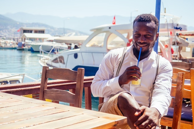 Handsome african american business man with healthy smoothie in summer beach tropical cafe in Turkey.