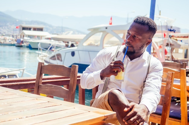 Handsome african american business man with healthy smoothie in summer beach tropical cafe in Turkey