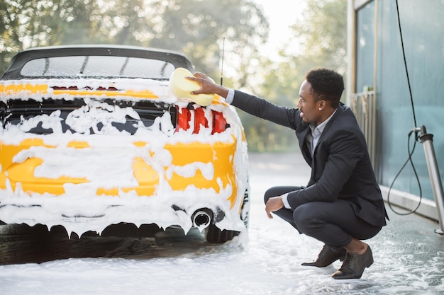 Handsome African American man iin business suit washing the Back lights headlight