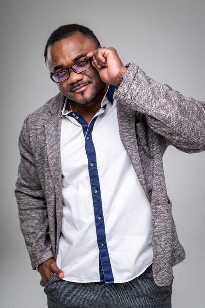 Handsome African American man in white shirt standing against grey background. Closeup.