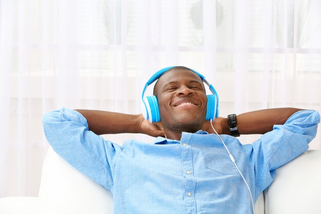 Photo handsome african american man with headphones lying on sofa close up