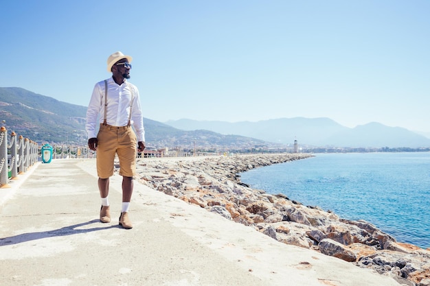 handsome african american person casual fashion look outfit in straw hat,white shirt walking by Tyrkey coast