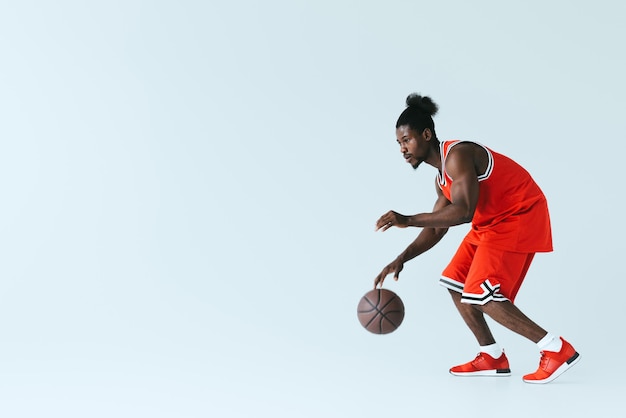 Photo handsome african american sportsman playing basketball on grey background with copy space