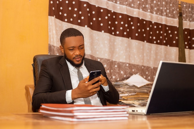 Handsome african business man going through his phone in the office