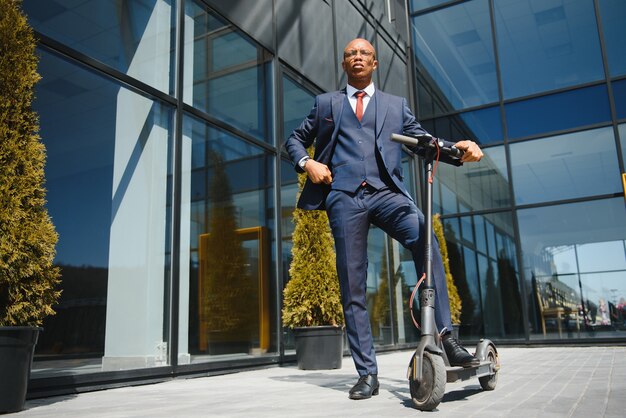 Handsome african businessman riding electric scooter outdoors