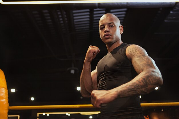 Handsome African male boxing fighter training at the gym