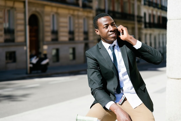 Handsome african man with mobile phone and fixed gear bicycle in the street.