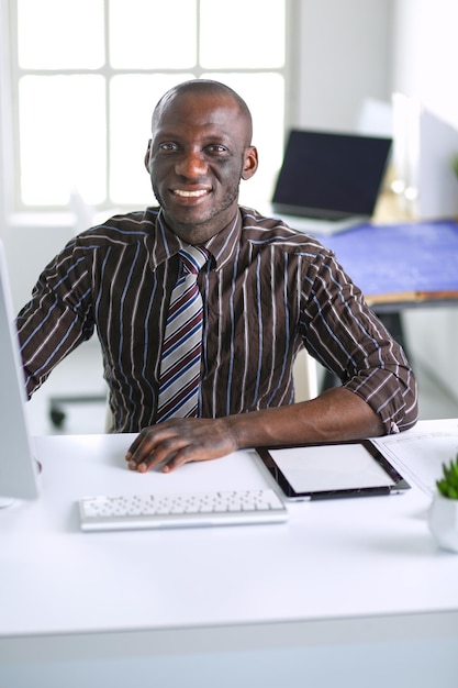 클래식 정장에 잘 생긴 아프리카 계 미국인 사업가 노트북을 사용하고 사무실에서 작업하는 동안 웃고