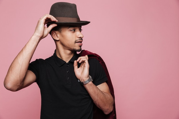 Handsome afro american man in hat holding jacket over shoulder