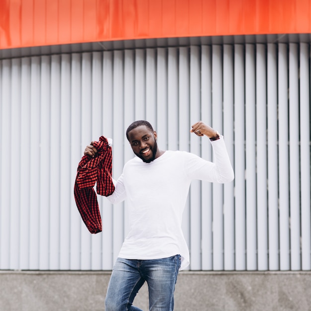 Handsome Afro American man wearing casual clothes jumping and dancing with grunge concrete wall background.