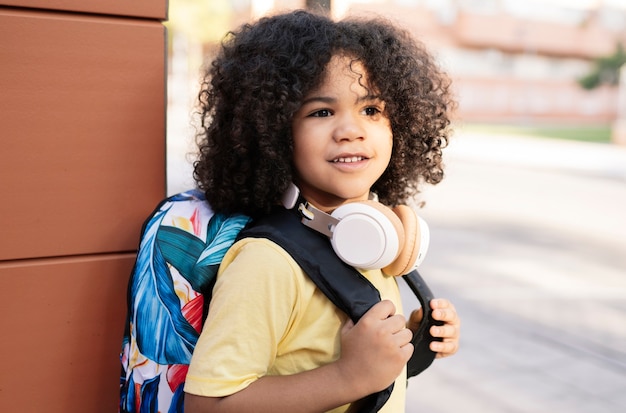 ハンサムなアフロ少年は学校のコンセプトにバックパックを運ぶ