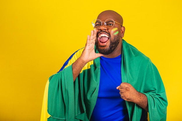 Handsome afro brazilian man wearing glasses brazilian fan brazil world cup 2022 vibrating screaming goal brazil goal happiness and euphoria jumping