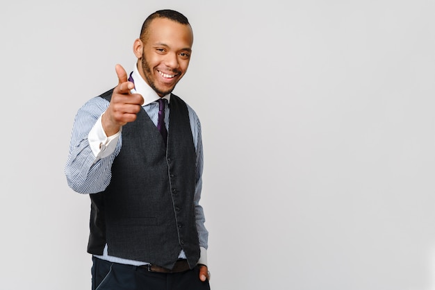 Uomo afroamericano bello che ti indica mentre stando contro la parete grigia